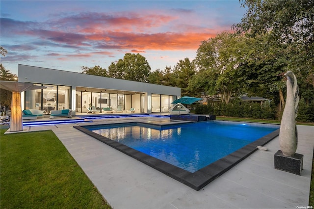 pool at dusk featuring a patio area and an outdoor living space