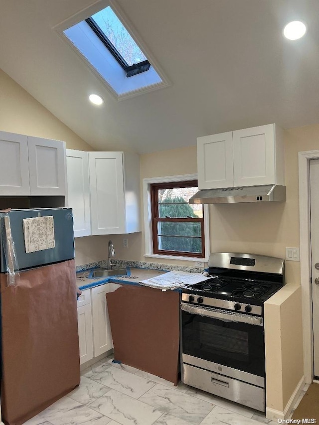 kitchen with white cabinetry, sink, stainless steel gas range oven, black fridge, and lofted ceiling with skylight