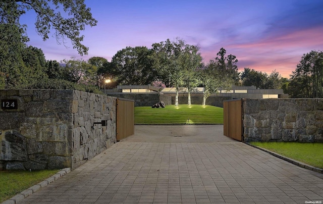 gate at dusk with a yard and a patio