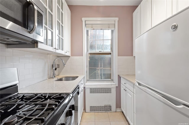 kitchen featuring light stone countertops, stainless steel appliances, sink, white cabinets, and light tile patterned flooring