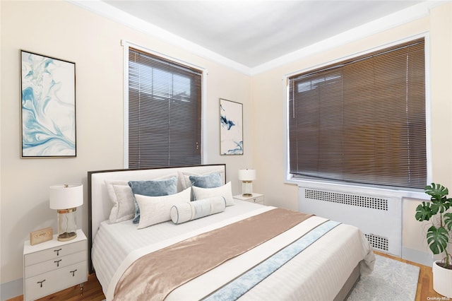 bedroom featuring radiator heating unit and hardwood / wood-style flooring