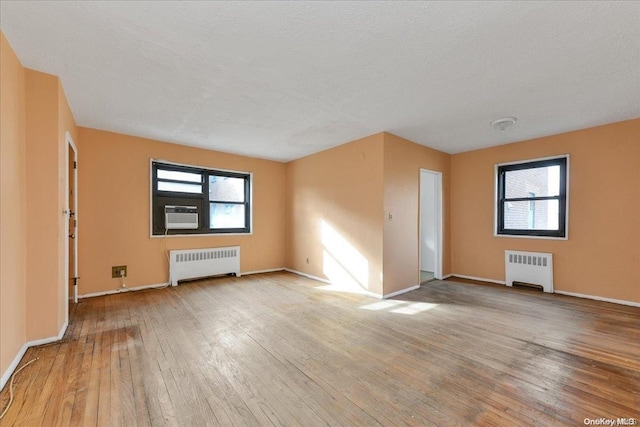 spare room with radiator heating unit, light hardwood / wood-style flooring, and plenty of natural light