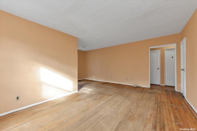 unfurnished room with light wood-type flooring and a textured ceiling