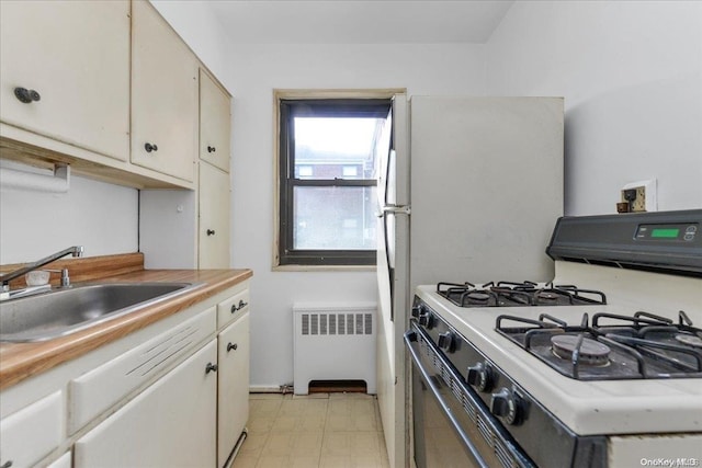 kitchen with white cabinets, radiator heating unit, sink, and gas range gas stove