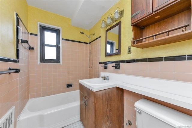 full bathroom with vanity, tiled shower / bath, tile patterned flooring, toilet, and tile walls