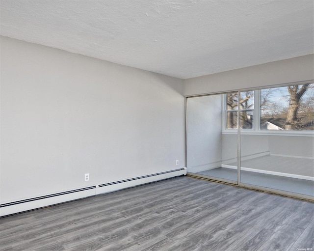 222 Smith St Unit 3C, Freeport, NY 11520 - unfurnished bedroom with wood finished floors, a baseboard heating unit, a textured ceiling, a closet, and baseboards
