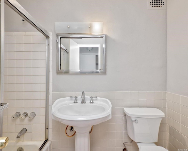 222 Smith St Unit 3C, Freeport, NY 11520 - full bath featuring toilet, bath / shower combo with glass door, tile walls, and wainscoting