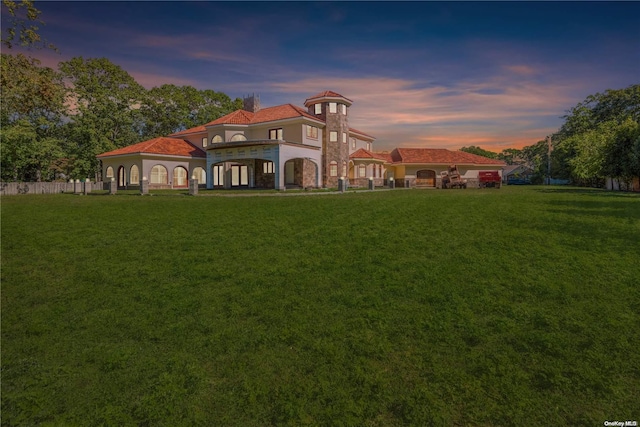 back house at dusk with a yard and a balcony