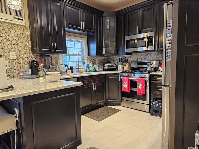 kitchen with backsplash, light stone counters, stainless steel appliances, sink, and light tile patterned floors