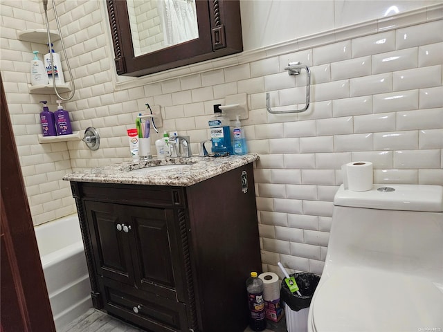 bathroom featuring decorative backsplash, vanity, a bath, tile walls, and toilet