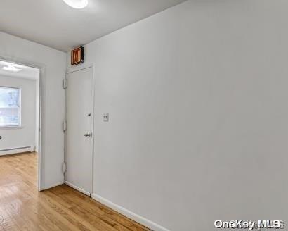 unfurnished room featuring light wood-type flooring and a baseboard radiator