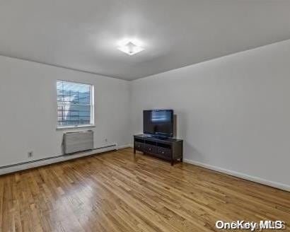 unfurnished living room featuring hardwood / wood-style floors and a baseboard heating unit