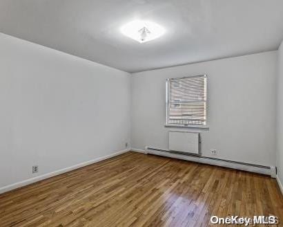 spare room with wood-type flooring and baseboard heating