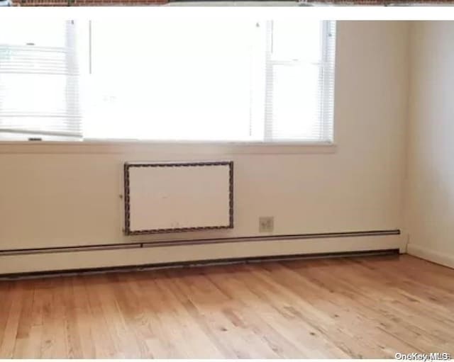 empty room with light hardwood / wood-style flooring, baseboard heating, and a wealth of natural light