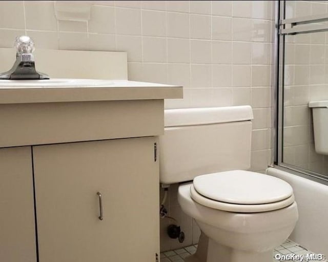 bathroom featuring vanity, a shower with door, toilet, and tile walls