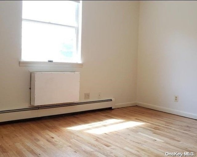 unfurnished room with baseboard heating and light hardwood / wood-style flooring