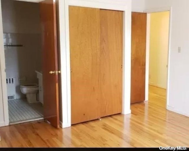 unfurnished bedroom with connected bathroom, light hardwood / wood-style flooring, and radiator