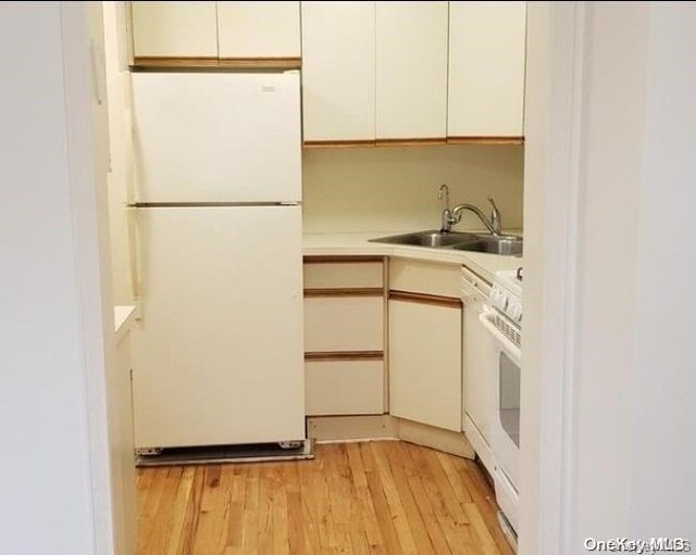 kitchen featuring white cabinetry, sink, white appliances, and light wood-type flooring