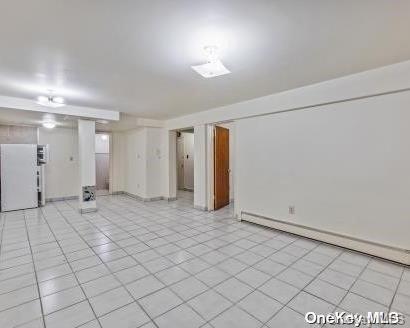 interior space featuring baseboard heating, light tile patterned flooring, and white refrigerator