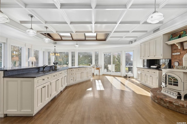 kitchen with sink, hanging light fixtures, coffered ceiling, and light hardwood / wood-style flooring