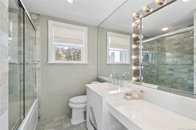 full bathroom with enclosed tub / shower combo, tile patterned floors, toilet, vanity, and tile walls