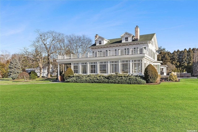 rear view of property featuring a balcony and a lawn