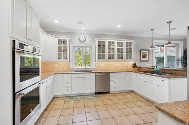 kitchen with white cabinetry, sink, light stone countertops, decorative light fixtures, and appliances with stainless steel finishes