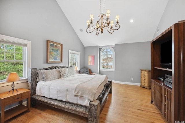 bedroom with light hardwood / wood-style floors, high vaulted ceiling, and an inviting chandelier