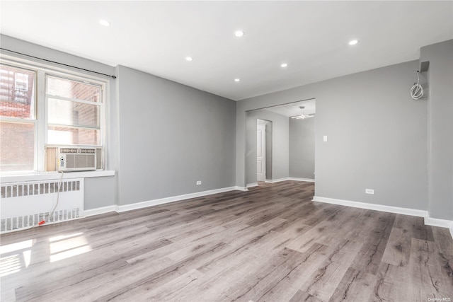 unfurnished room featuring radiator heating unit, cooling unit, and light hardwood / wood-style floors