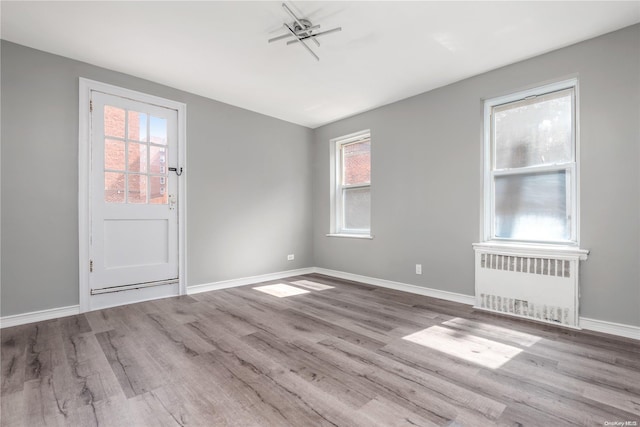 unfurnished room with radiator, a wealth of natural light, and light hardwood / wood-style flooring