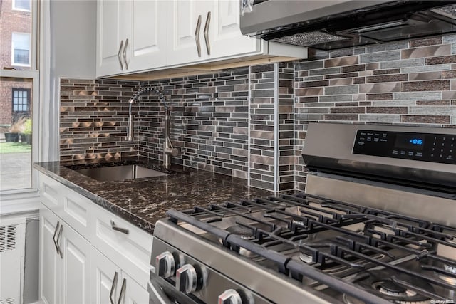 kitchen featuring appliances with stainless steel finishes, backsplash, sink, dark stone countertops, and white cabinets