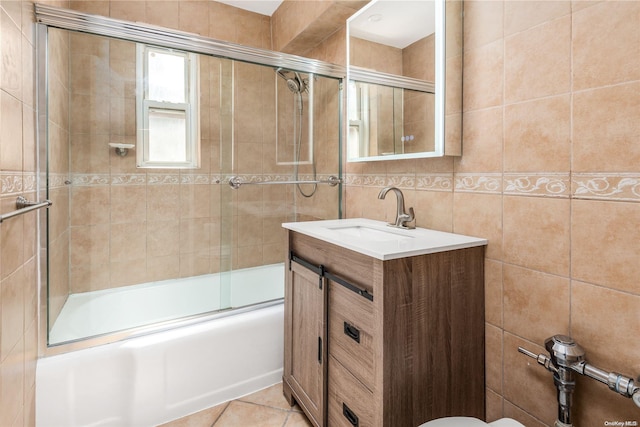 full bathroom with tile patterned floors, vanity, shower / bath combination with glass door, tile walls, and toilet