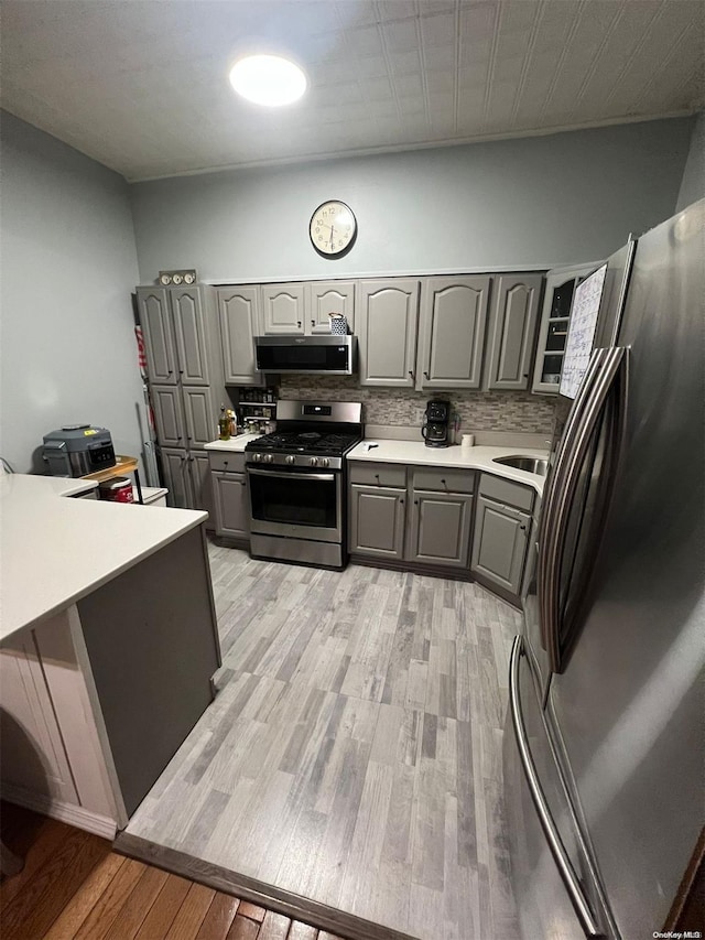 453 Ridgewood Ave, Brooklyn, NY 11208 - kitchen featuring appliances with stainless steel finishes, gray cabinets, tasteful backsplash, light wood-type flooring, and light countertops