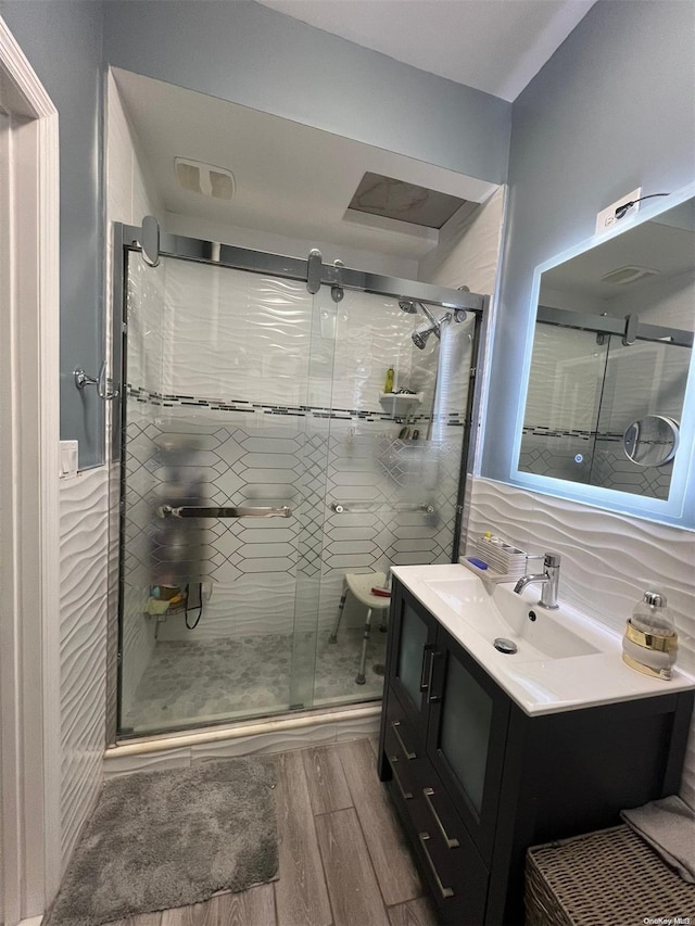 bathroom with tasteful backsplash, a shower with door, vanity, and wood-type flooring