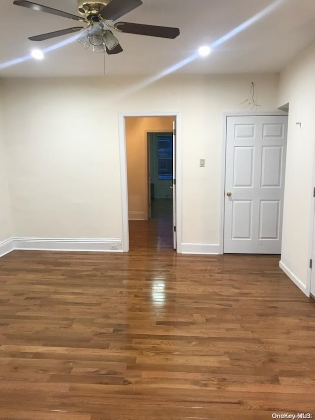 empty room with ceiling fan and dark hardwood / wood-style flooring