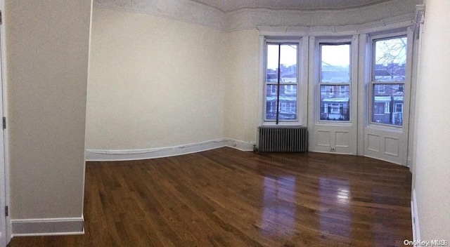 empty room featuring radiator and dark wood-type flooring