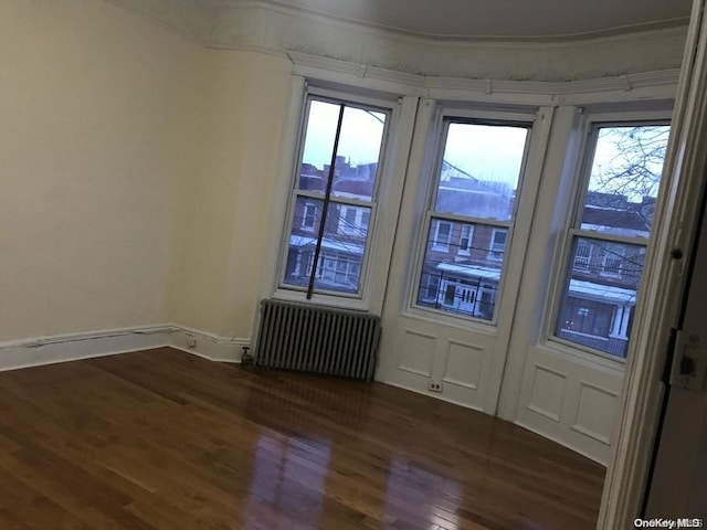 doorway to outside featuring radiator heating unit, dark hardwood / wood-style flooring, and ornamental molding