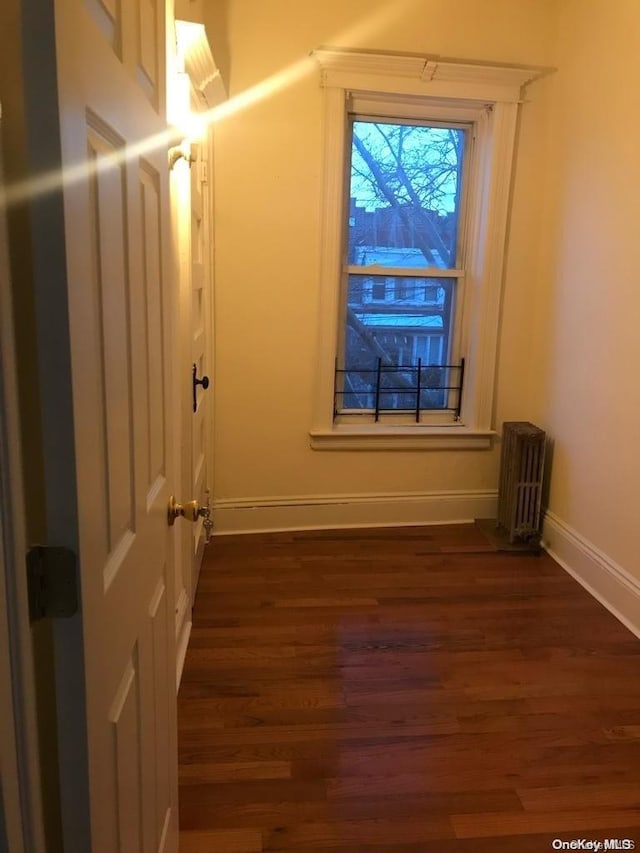 interior space with radiator heating unit and dark hardwood / wood-style floors