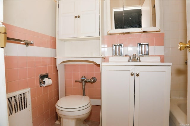 bathroom featuring radiator, vanity, tile walls, and toilet