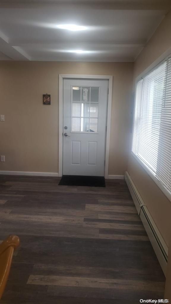 doorway to outside with baseboard heating and dark wood-type flooring