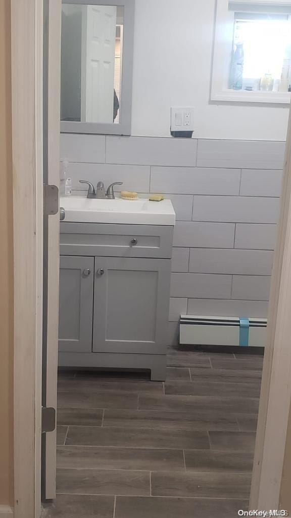 bathroom with vanity, hardwood / wood-style flooring, and baseboard heating