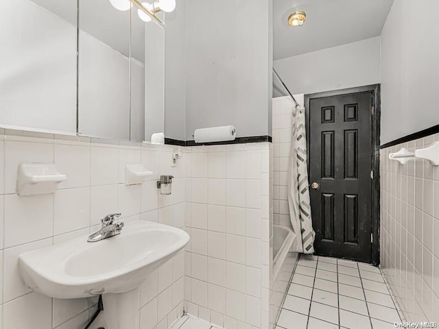 bathroom with tile patterned floors, sink, shower / bathtub combination with curtain, and tile walls