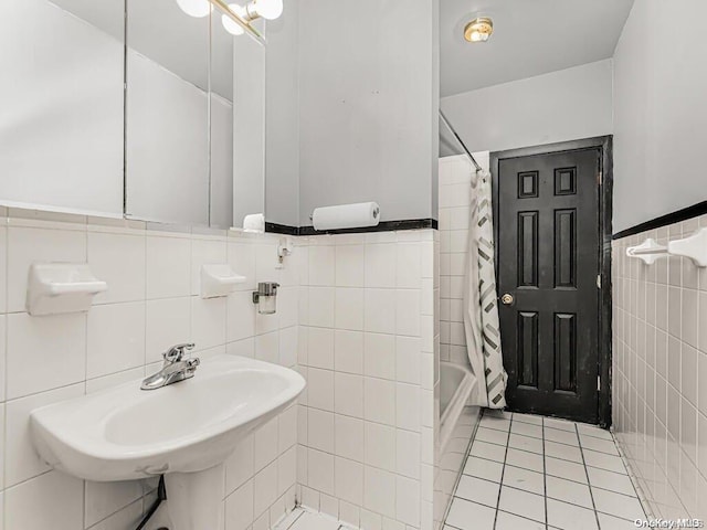 41 Convent Ave Unit 5N, New York Manhattan, NY 10027 - bathroom featuring tile walls, tile patterned flooring, shower / bath combination with curtain, a sink, and a wainscoted wall
