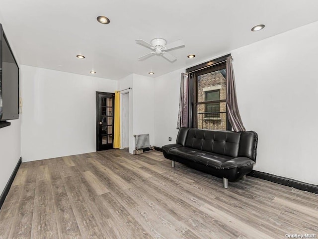 sitting room with ceiling fan, radiator heating unit, and light hardwood / wood-style floors