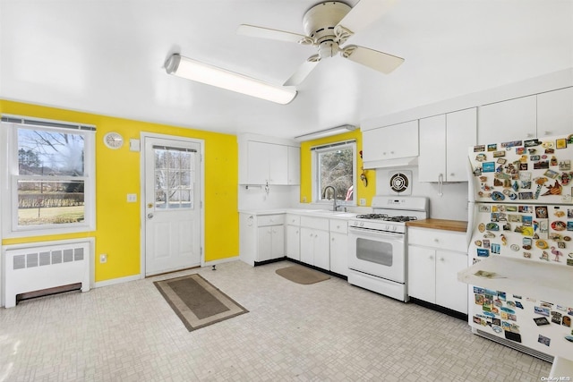 kitchen with radiator, white appliances, ceiling fan, sink, and white cabinetry