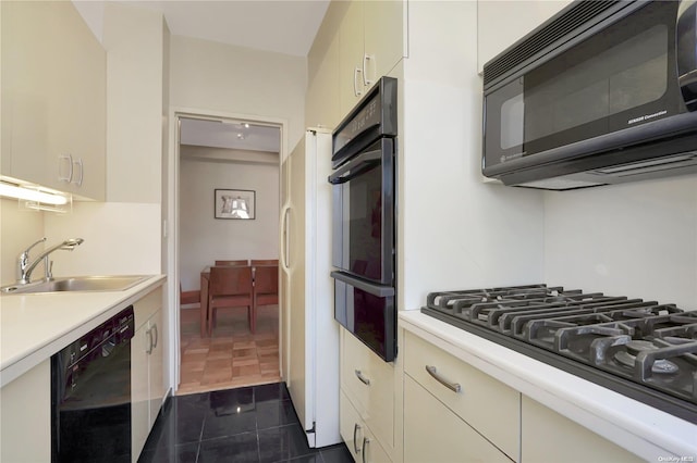 kitchen featuring cream cabinets, sink, black appliances, and dark tile patterned flooring