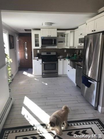 kitchen featuring white cabinets, backsplash, stainless steel appliances, and sink