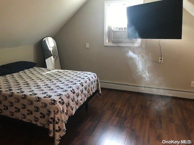 bedroom with baseboard heating, dark hardwood / wood-style flooring, and vaulted ceiling