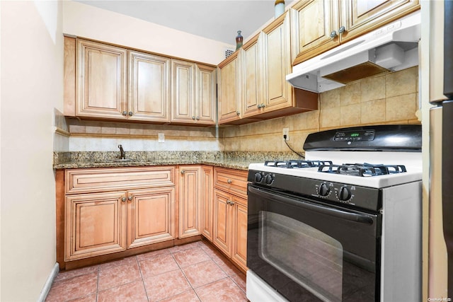 kitchen with stone countertops, sink, light tile patterned floors, tasteful backsplash, and white gas stove