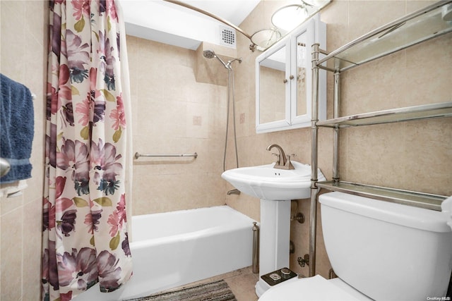 bathroom with tile patterned floors, toilet, tile walls, and shower / tub combo with curtain